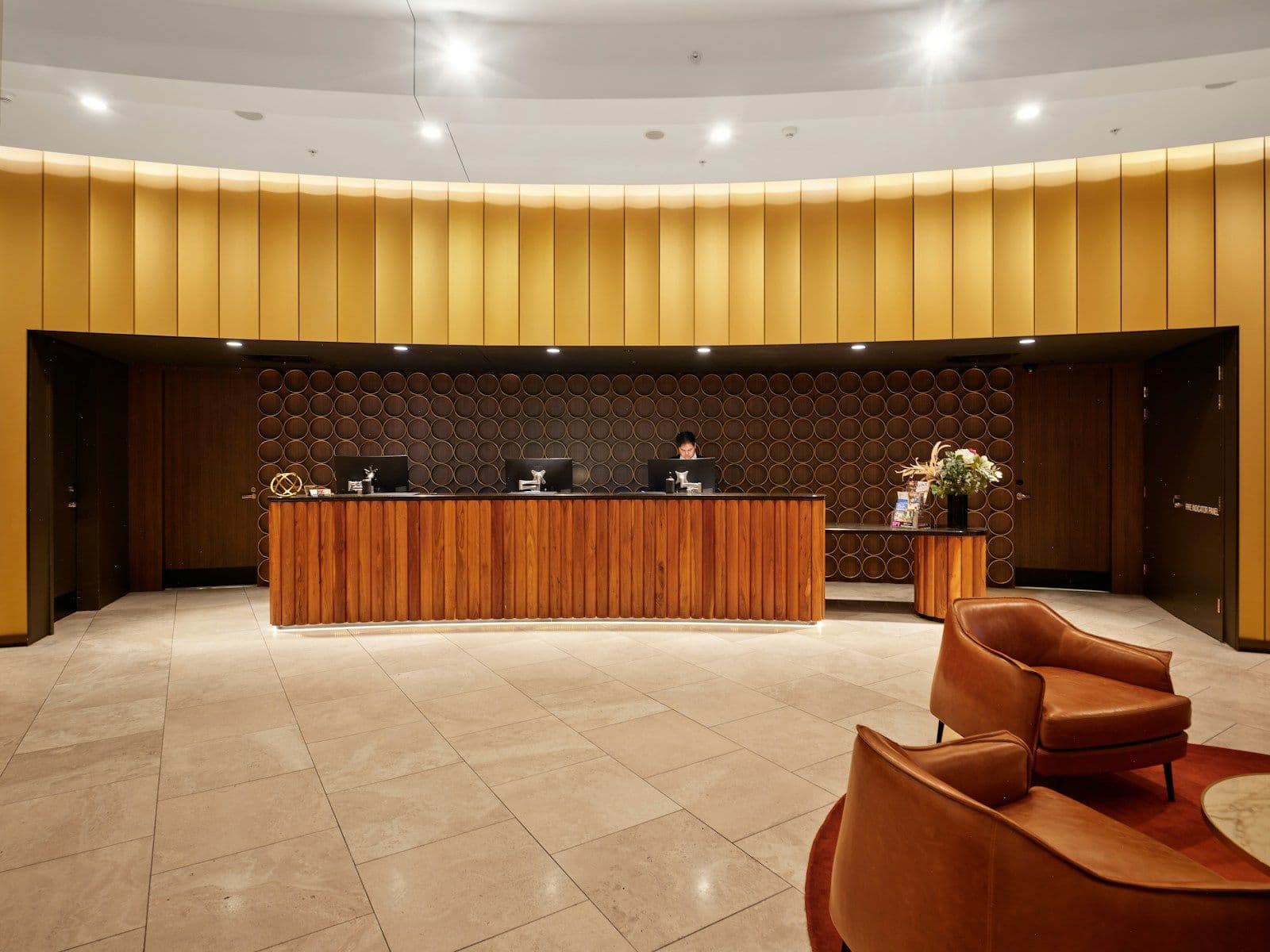 A hotel reception desk with leather armchairs in the lobby