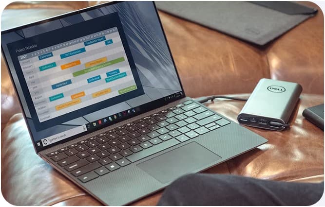 Laptop showing a project schedule next to a portable hard drive